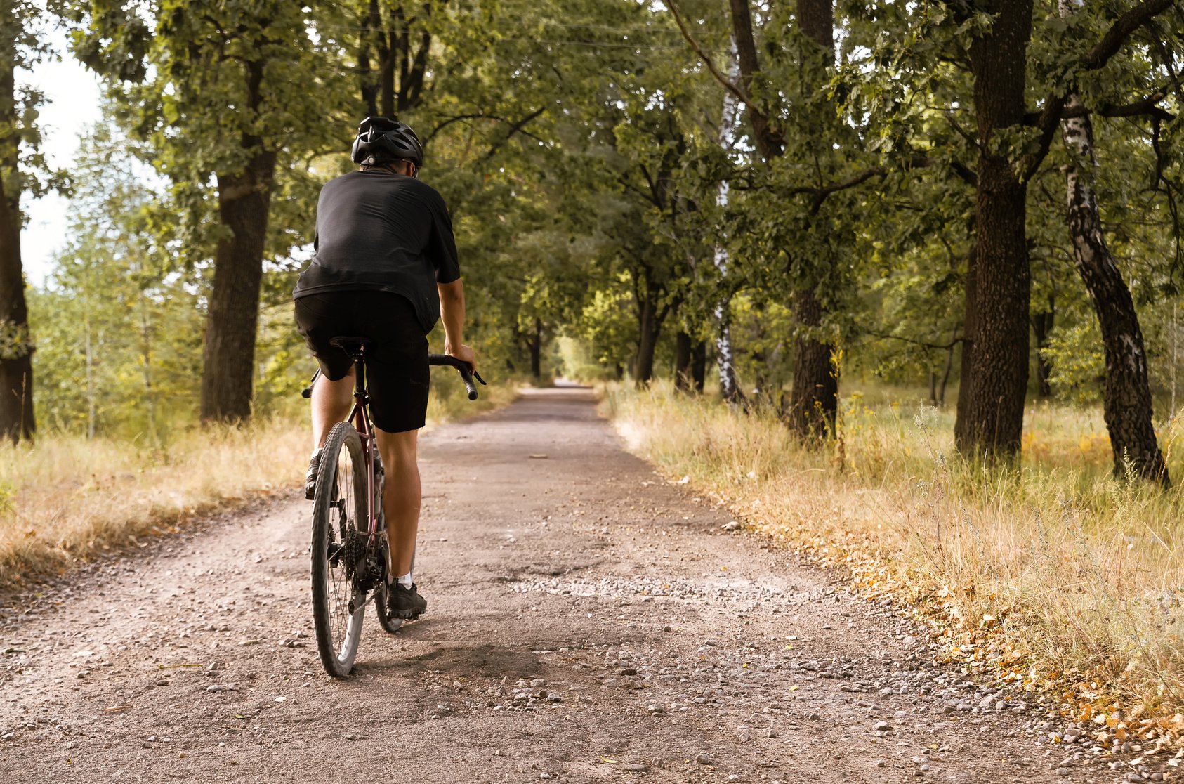 Cyclist on a gravel bike rides along country road with pits.